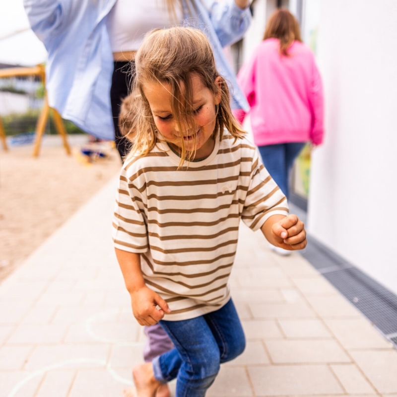 Ein Kind springt auf einer mit Kreide bemahlten Fläche in der Kita kinderzimmer Hamburg