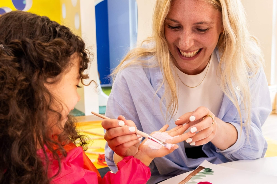 Pädagogin die einem Kind Fingerfarbe aufrägt in der Kita kinderzimmer Hamburg