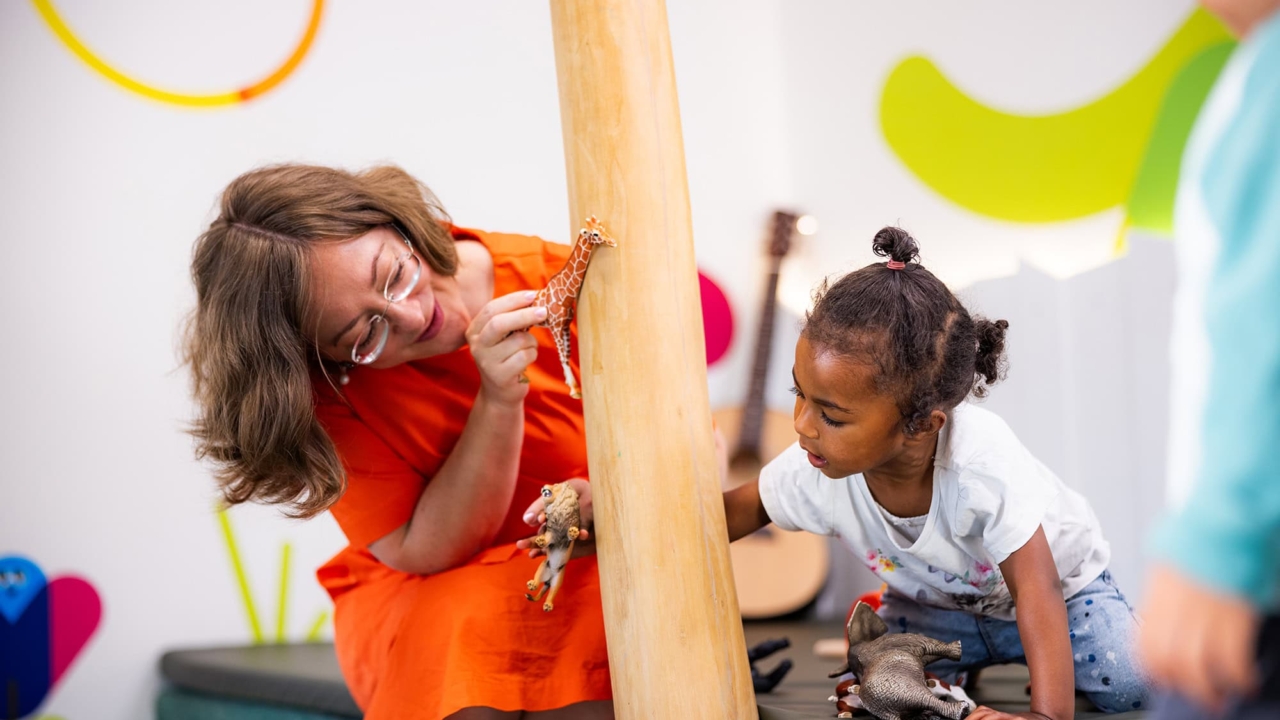 Eine Pädagogin zeigt einem Kind eine Giraffe in der Kita kinderzimmer Hamburg