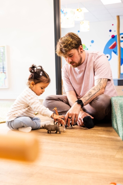 Ein Erzieher spielt zusammen mit einem Kind mit Zoofiguren in der Kita kinderzimmer Hamburg