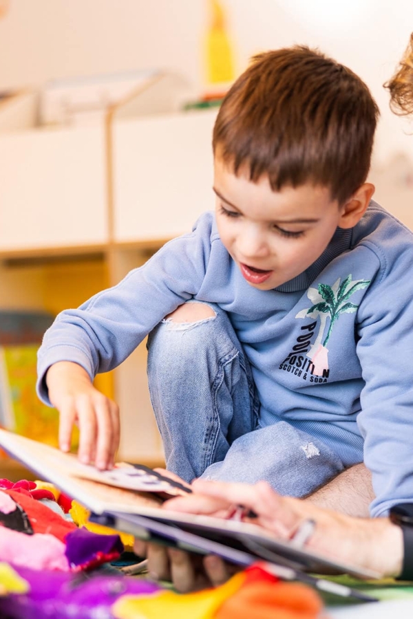 Ein Erzieher und ein Kind lesen zusammen ein Buch in der Kita kinderzimmer Hamburg