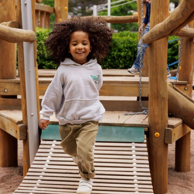 Junge läuft auf Spielplatz fröhlich auf Kamera zu