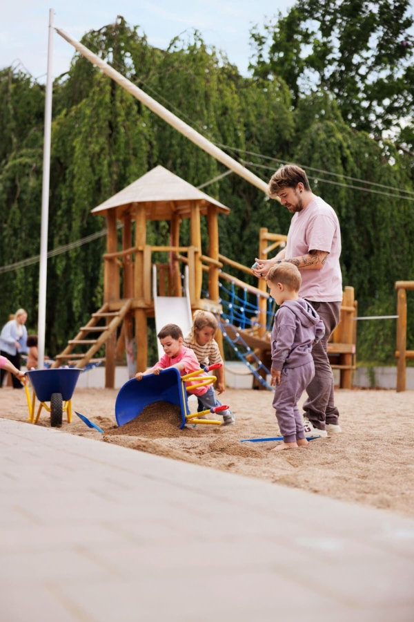 Pädagoge spielt mit vielen Kindern auf Spielplatz